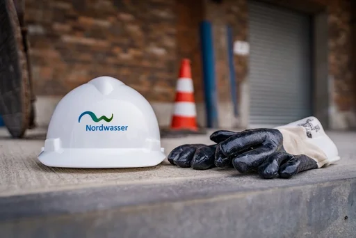 Um eine Baustelle zu symbolisieren ist ein Bauhelm, Arbeitshandschuhe und ein Pylon zu sehen