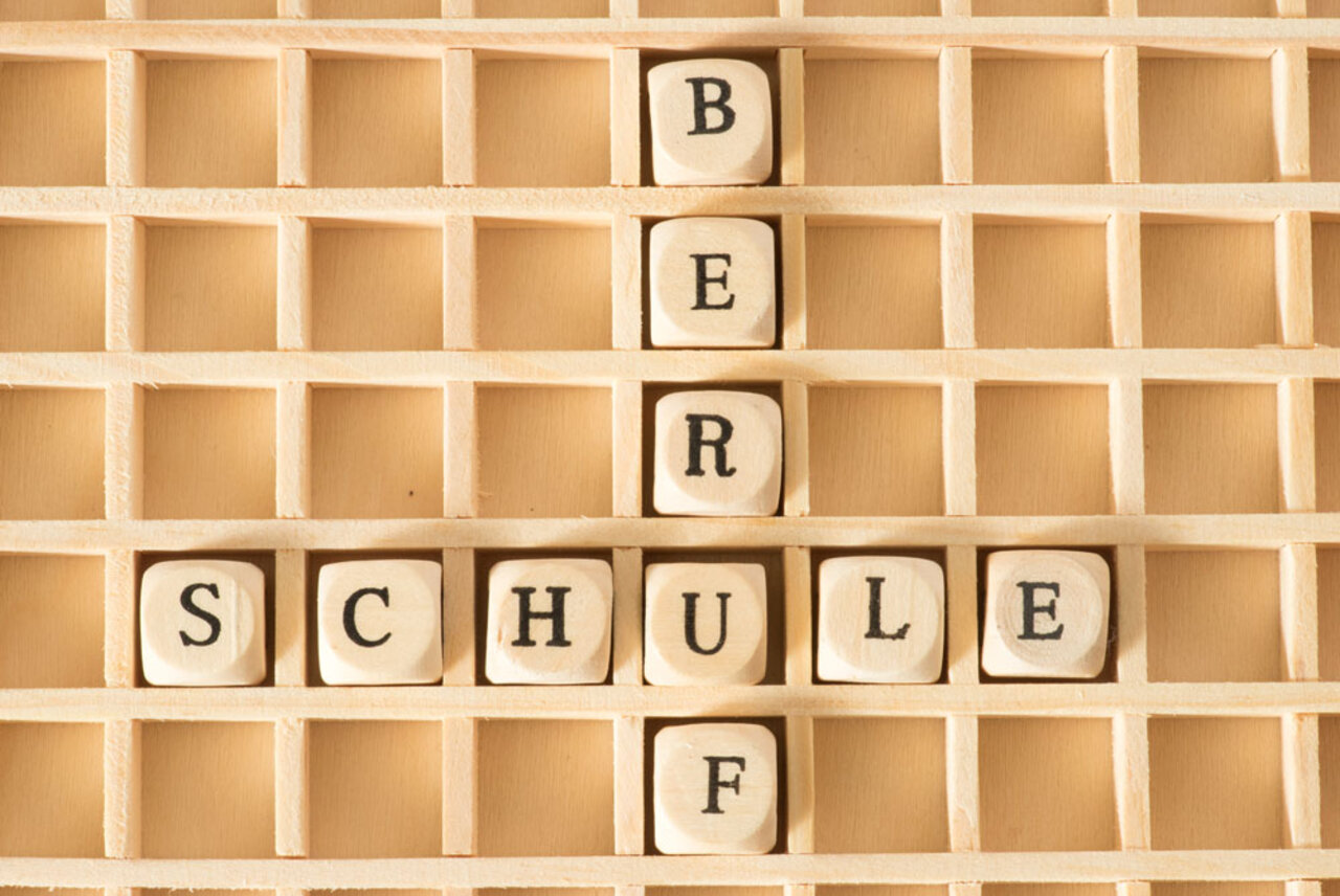 Holzgitter mit den Wörtern "BERUF" und "SCHULE" aus Buchstabenwürfeln.