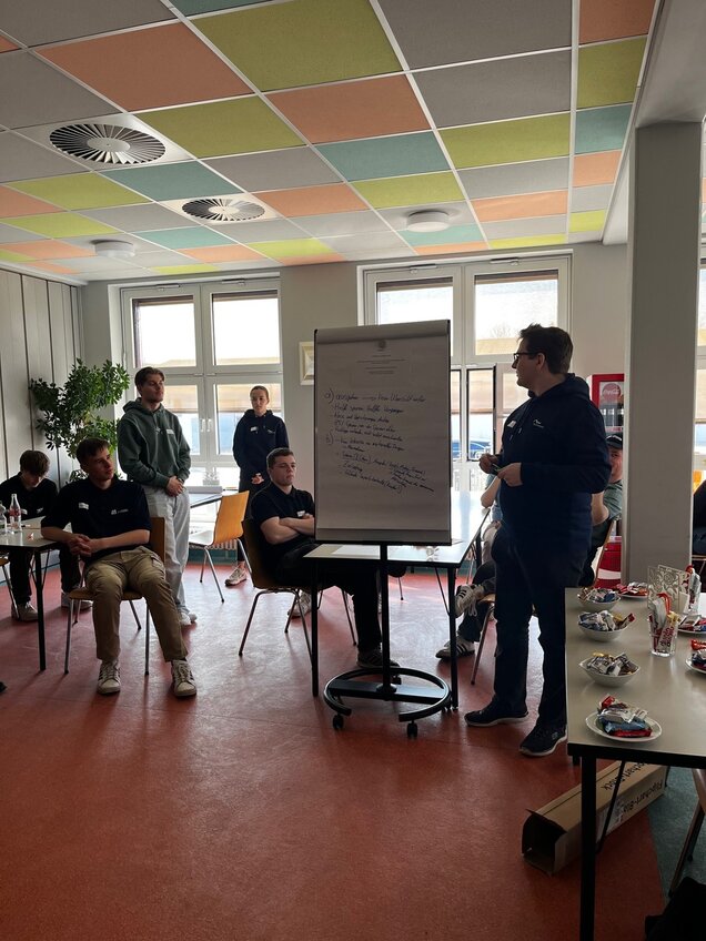 Auszubildender erklärt Inhalte auf einer Flipchart vor einer Gruppe