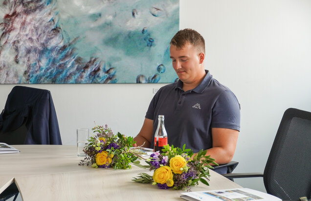 Jungfacharbeiter sitzt am Tisch und guckt aufs Zeugnis