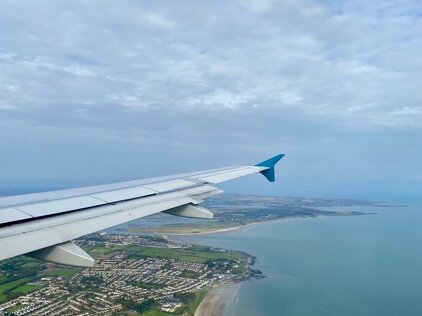 Foto eines Flugzeugflügels aus einem Flugzeug heraus, welches sich in der Luft befindet. 