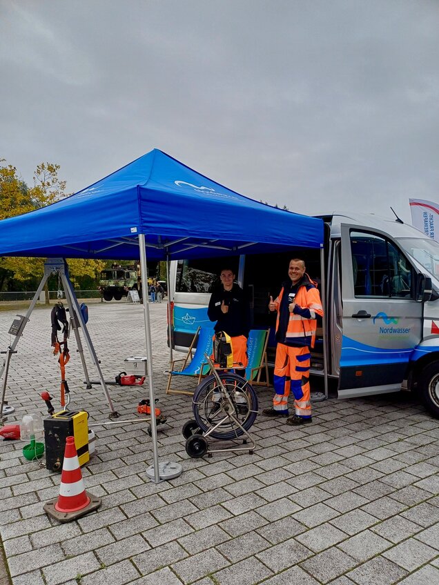 Azubis zeigen Daumen hoch und stehen an Nordwasser-Transporter