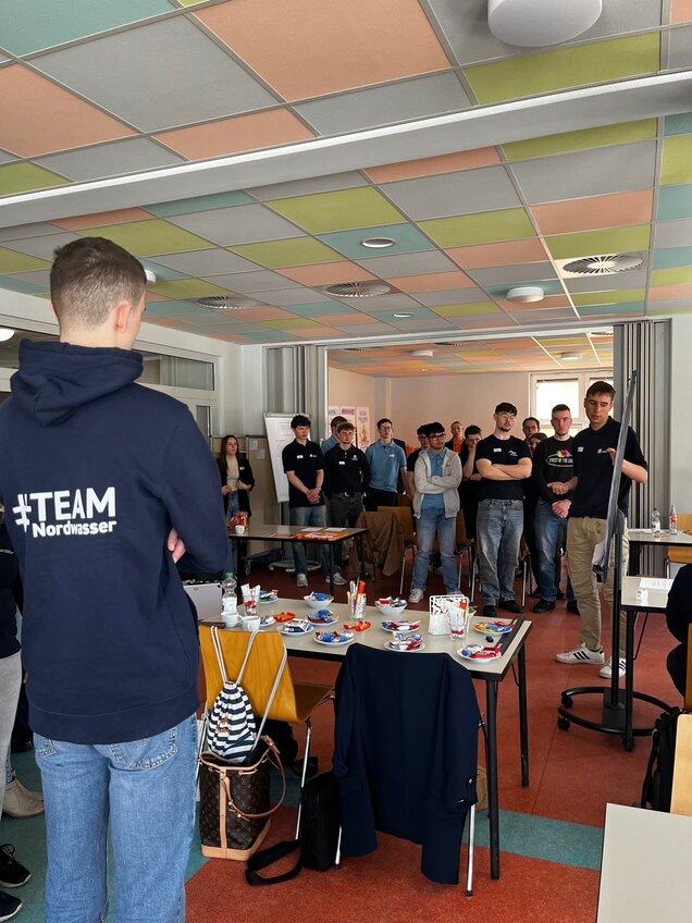 Auszubildender erklärt Inhalte auf einer Flipchart vor einer Gruppe